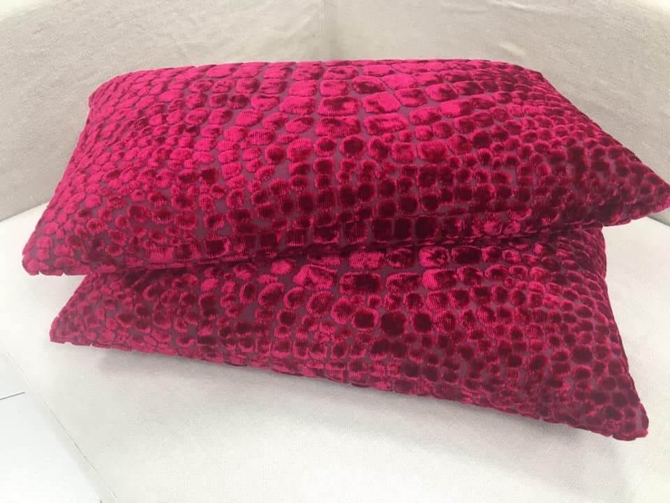 Due cuscini rosa sono impilati uno sopra l'altro su una superficie bianca.