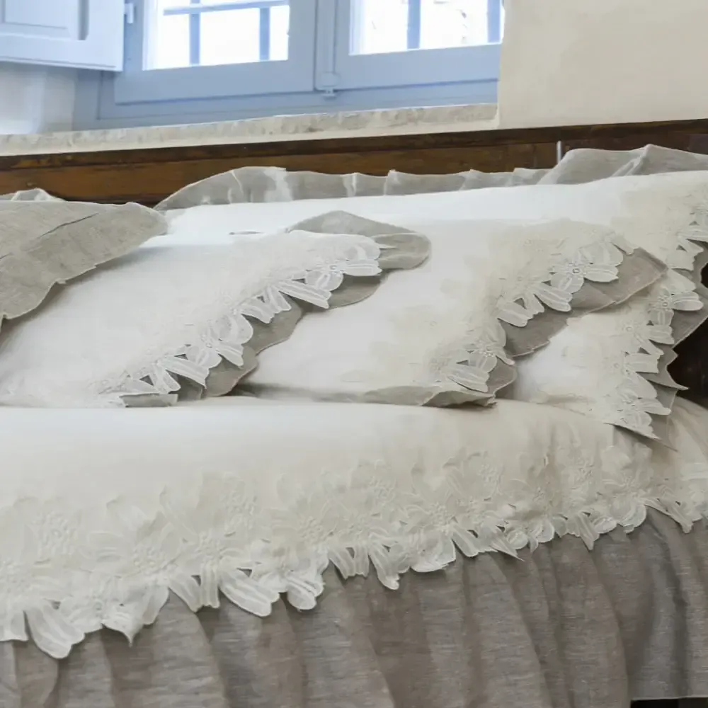 Un letto con cuscini arricciati e un piumone bianco