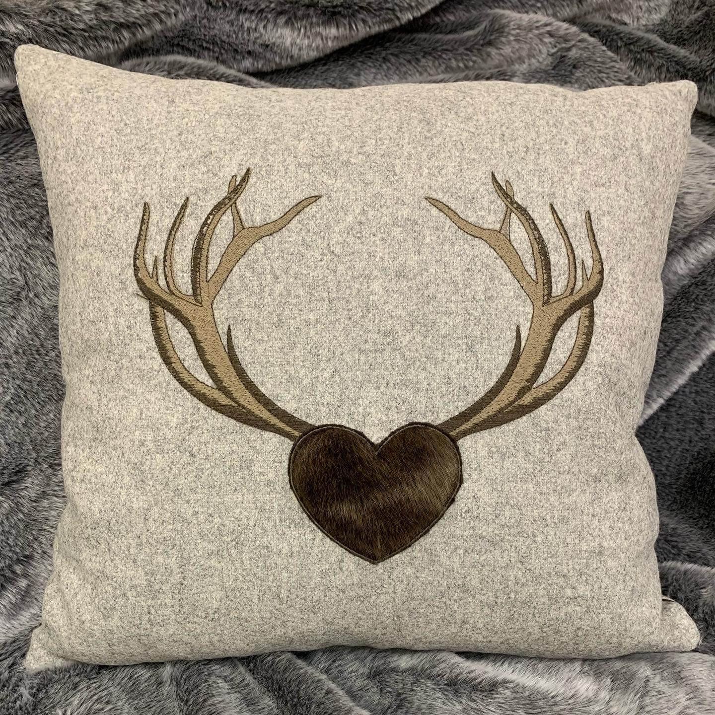 Un cuscino con delle corna di cervo e un cuore sopra è appoggiato su un letto.