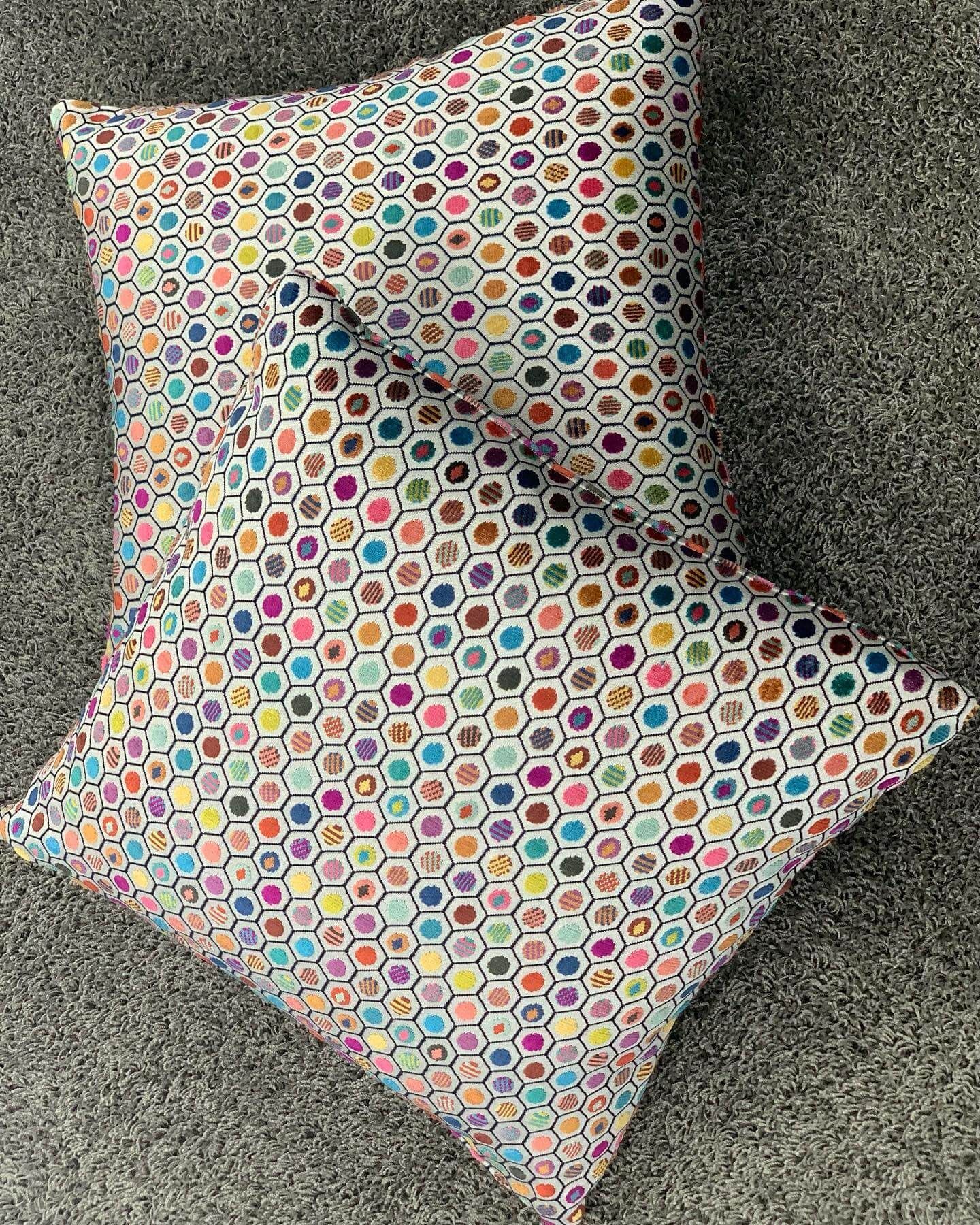 Due cuscini colorati sono appoggiati uno sopra l'altro su un tappeto.
