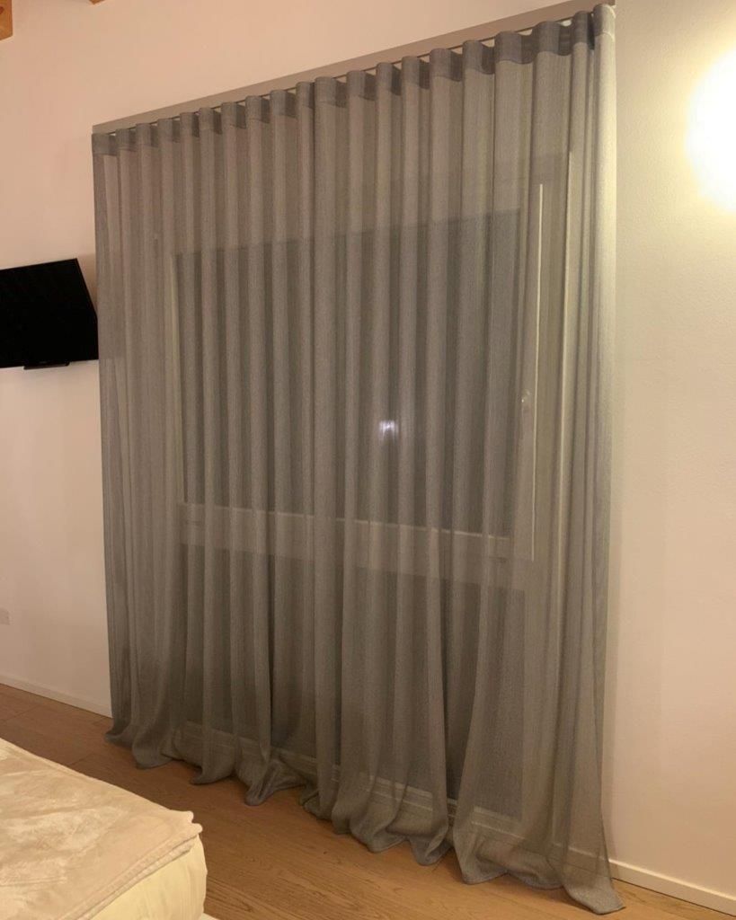 Una camera da letto con un letto e una finestra con tende trasparenti.