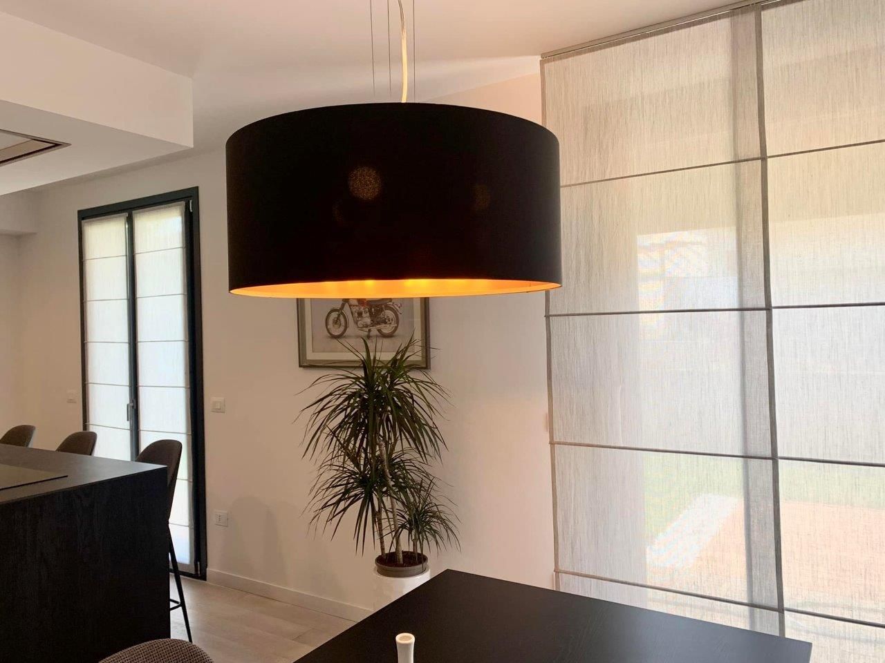 Una sala da pranzo con un tavolo nero e una lampada nera appesa al soffitto.