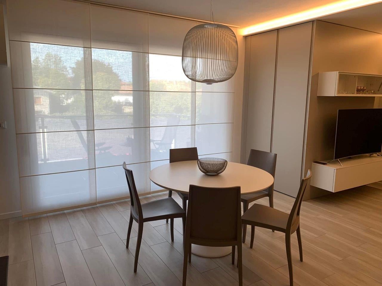 Una sala da pranzo con tavolo rotondo, sedie e TV a schermo piatto.