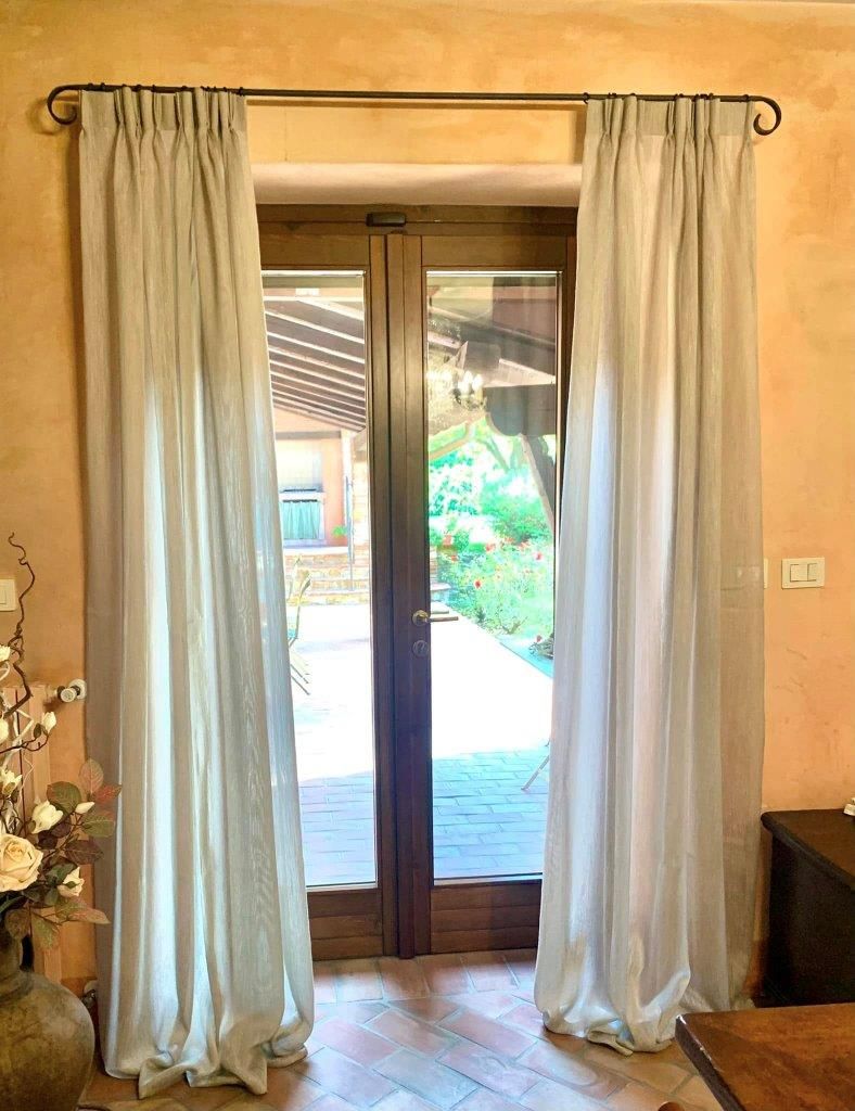 Un soggiorno con una porta scorrevole in vetro e tende bianche.