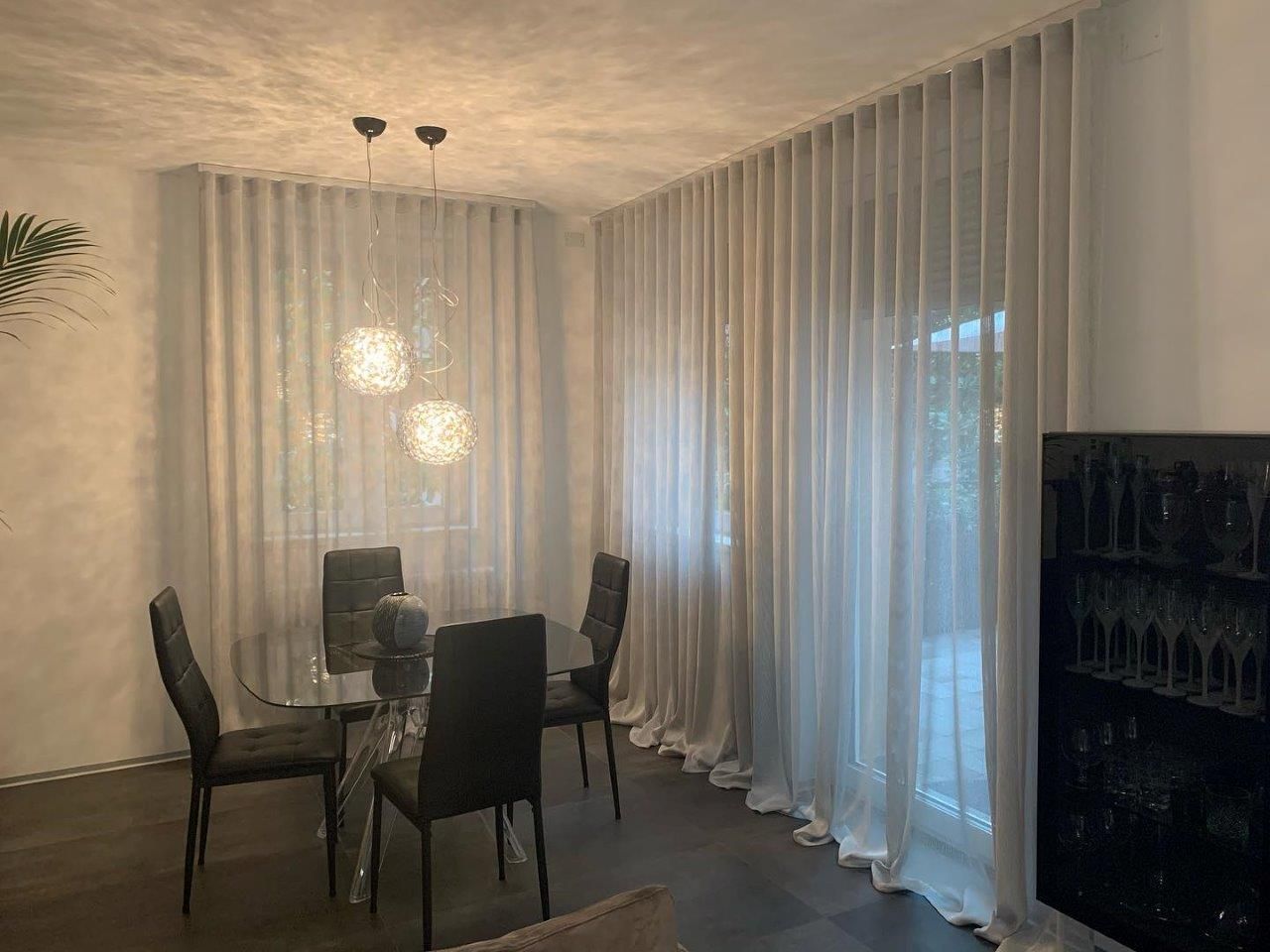 Una sala da pranzo con tavolo, sedie e tende bianche.
