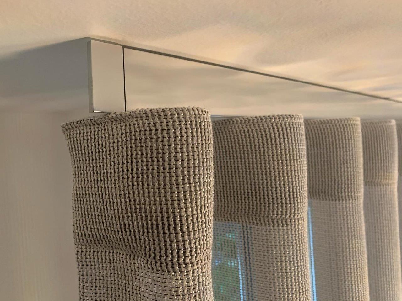 Primo piano di una finestra con le tende che pendono dal soffitto.