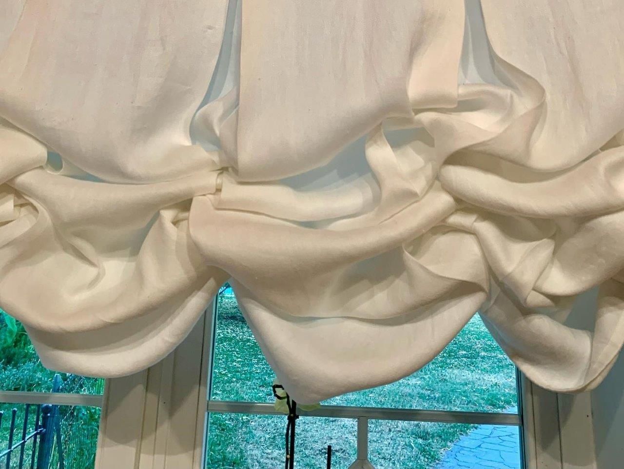 Una tenda bianca è appesa alla finestra di una stanza.