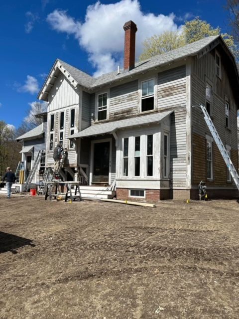 A large white house with a ladder in front of it.