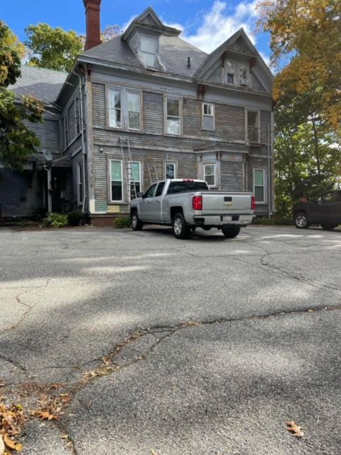A silver truck is parked in front of a large house
