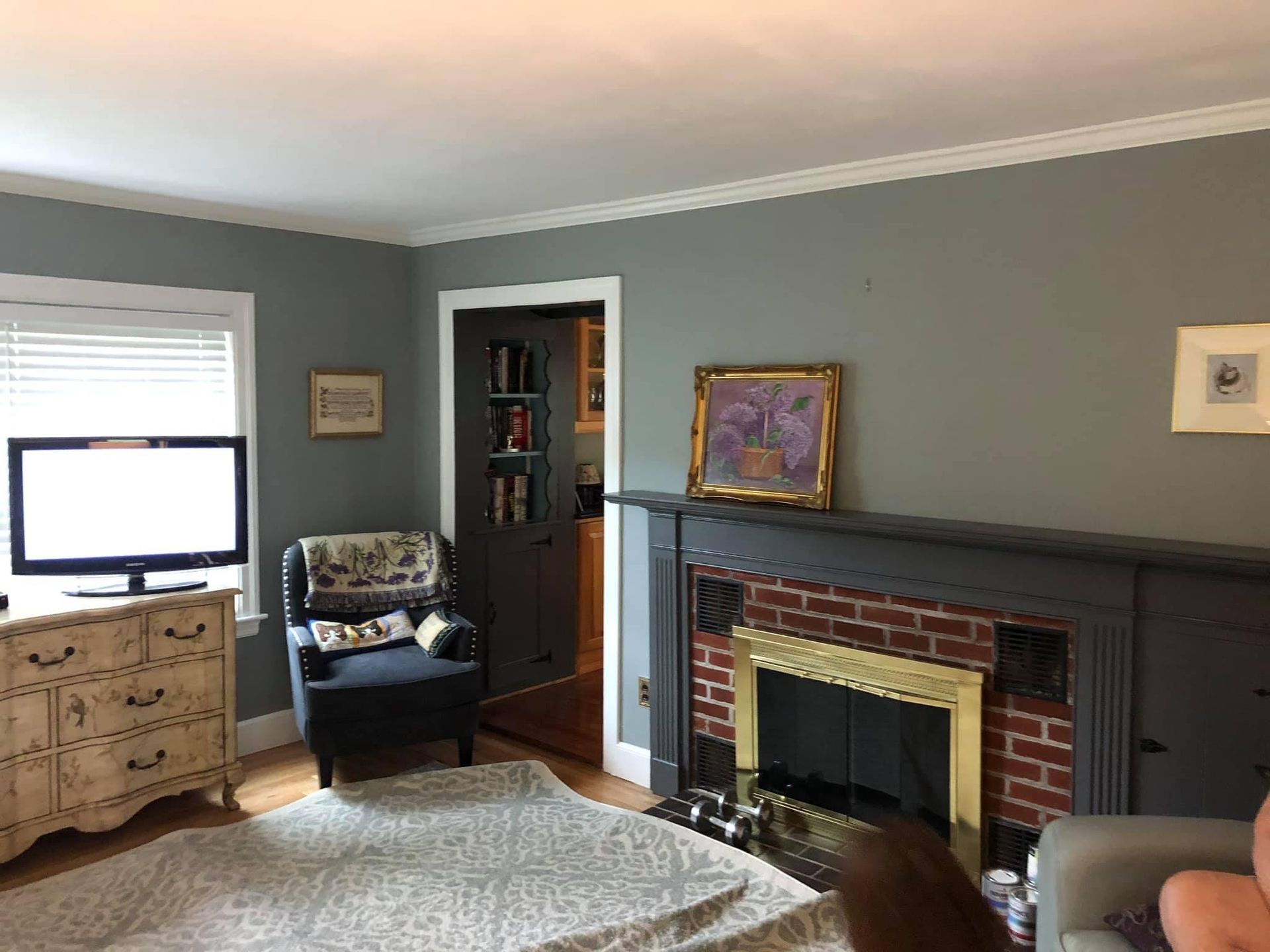 A living room with a fireplace , chair , dresser and television.