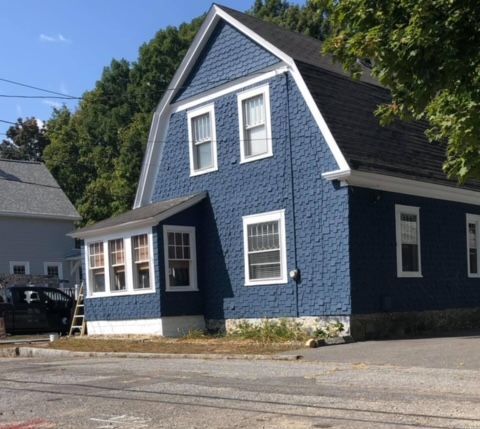 A blue house with a black car parked in front of it