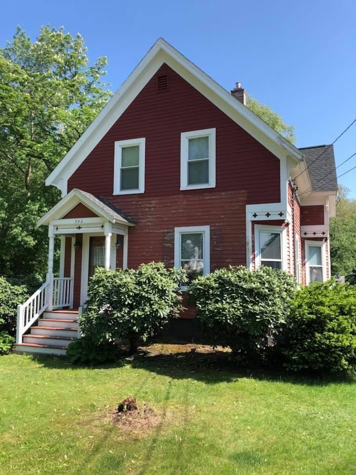 A red brick house with white trim and a white porch