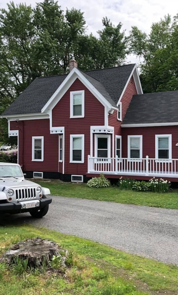 A red house with a white car parked in front of it.