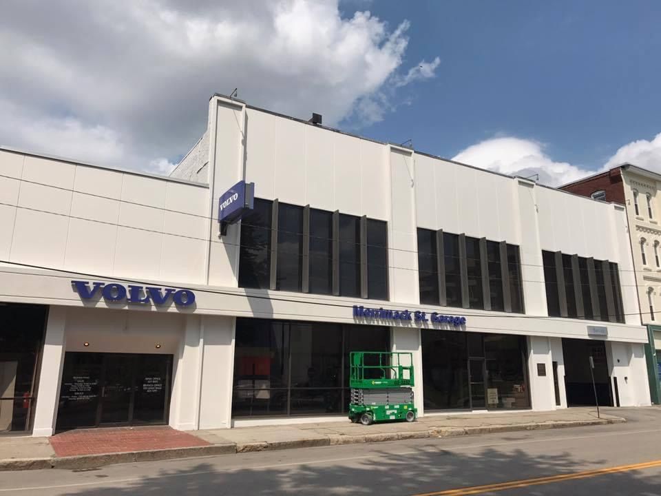 A volvo car dealership is located on the corner of a city street.
