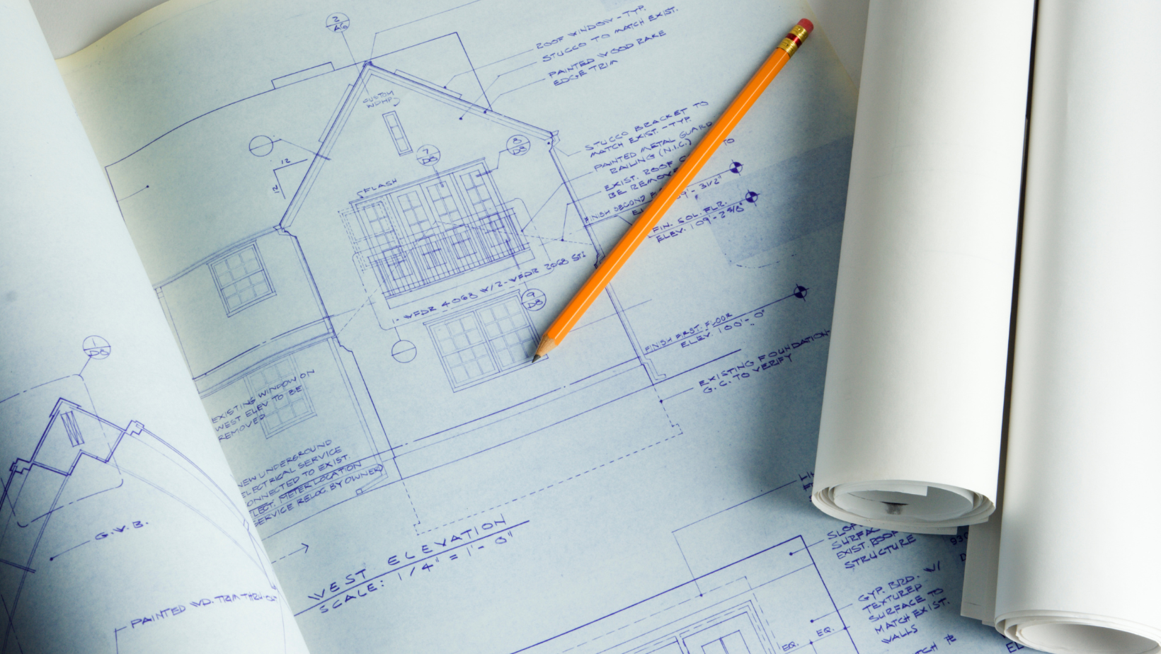 A pencil is sitting on top of a blueprint of a house.