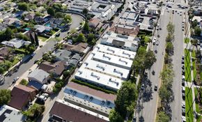 Aerial view of a suburban neighborhood with houses, trees, and a busy multi-lane street