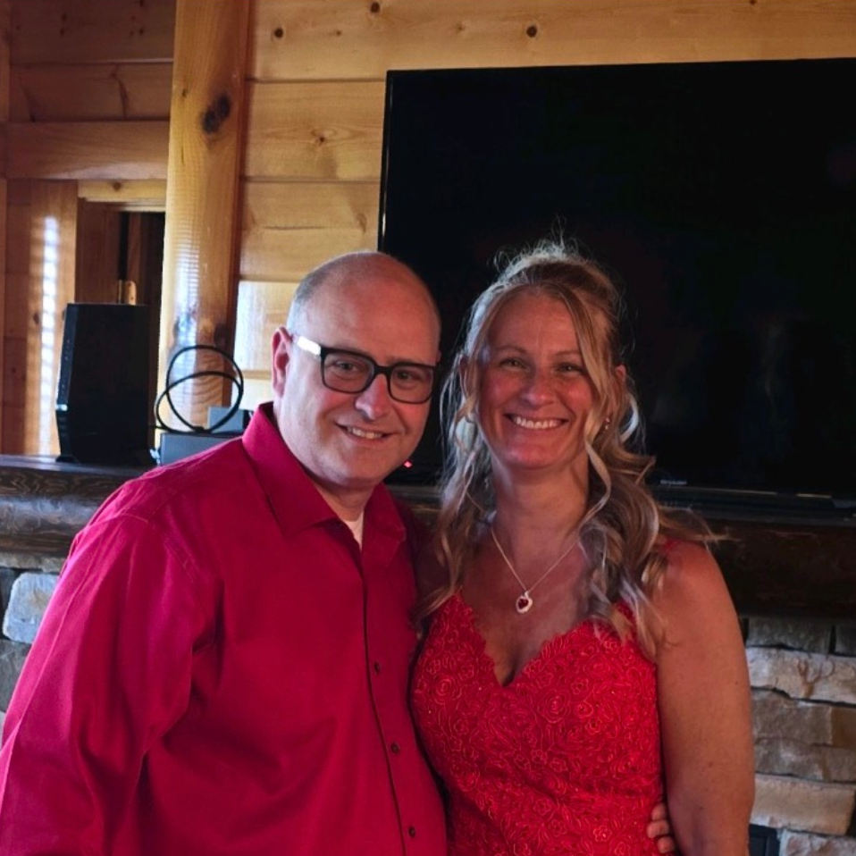 A man in a red shirt and a woman in a red dress are posing for a picture.