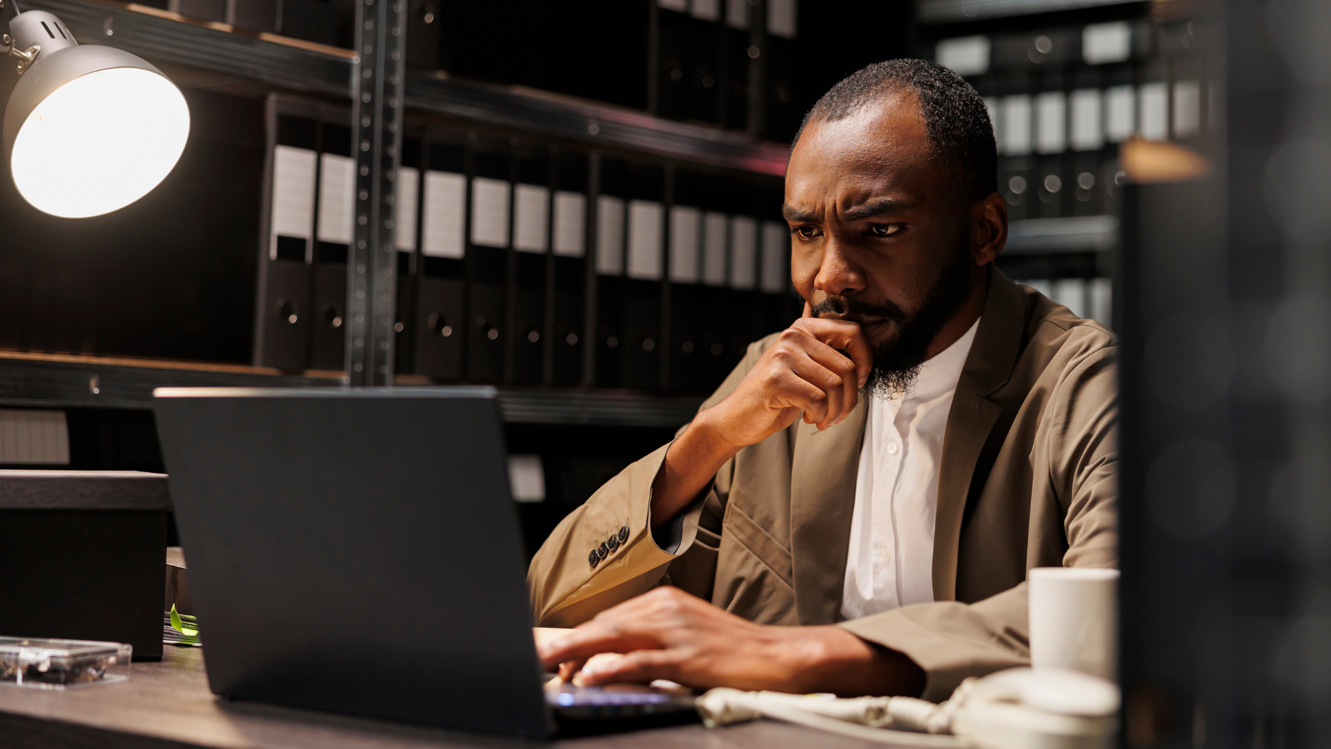 A man is sitting at a desk using a laptop computer.