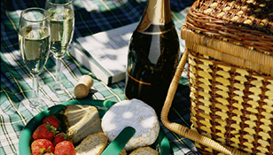 A picnic basket filled with food and a bottle of wine