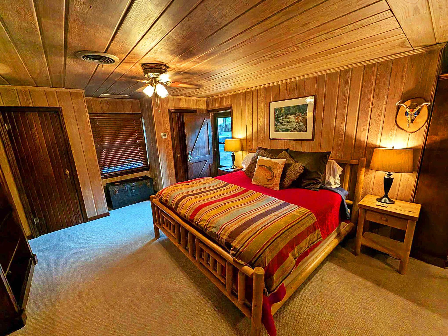 A bedroom with a king size bed and a ceiling fan.
