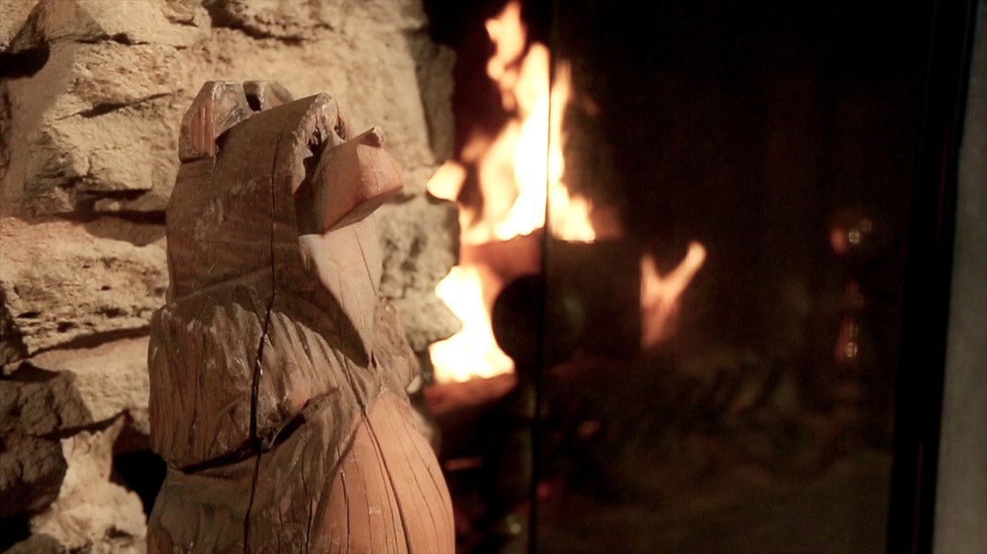 A wooden statue of a cat is sitting in front of a fireplace.