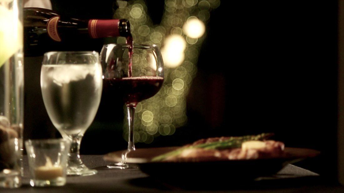 A bottle of wine is being poured into a glass on a table.