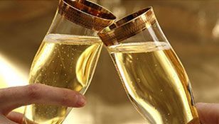 A person is holding two glasses of champagne in their hands.