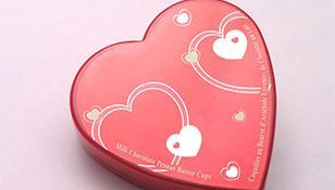A red heart shaped box with two white hearts on it.