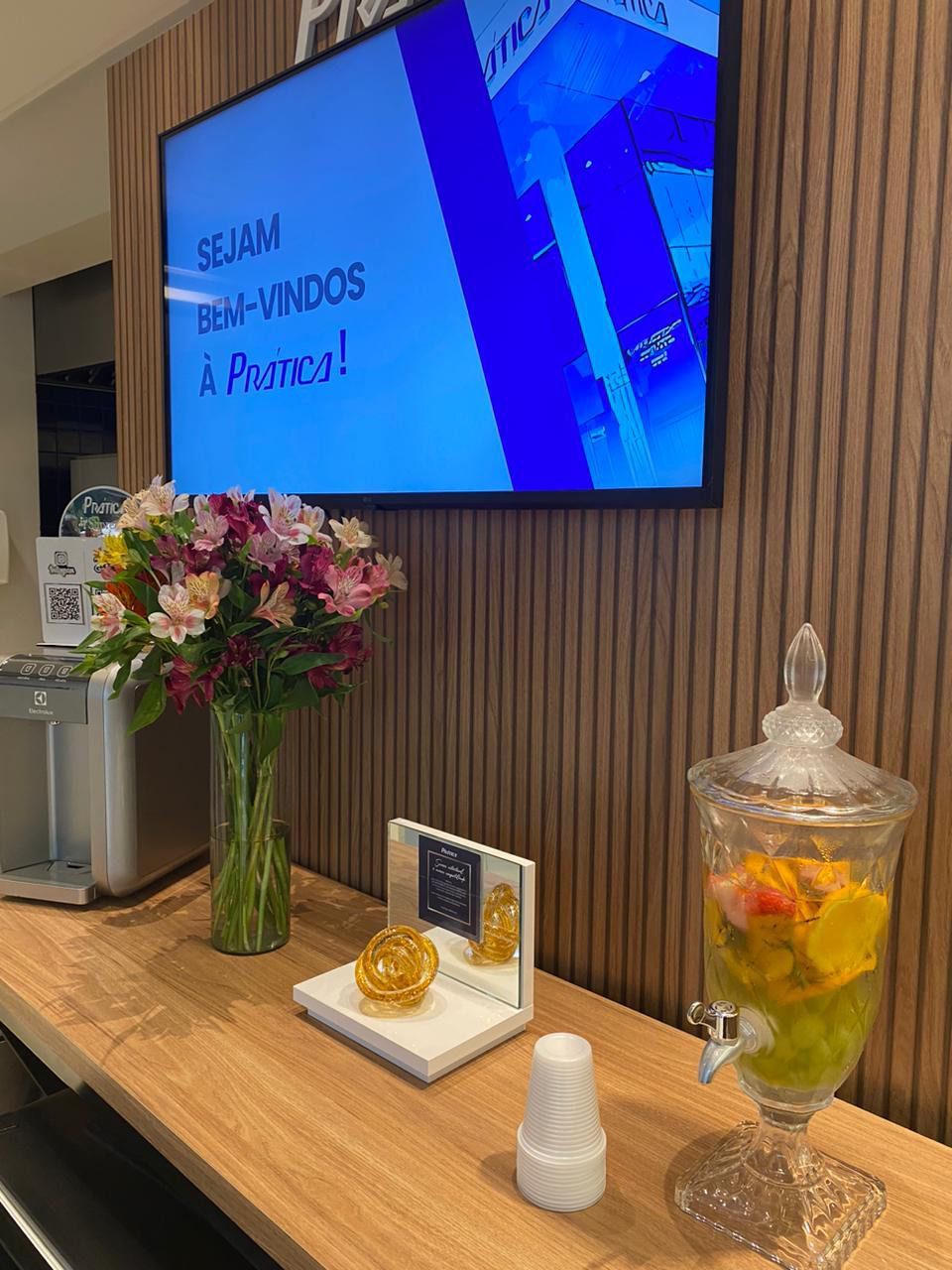 Uma mesa com um vaso de flores e uma tv na parede.
