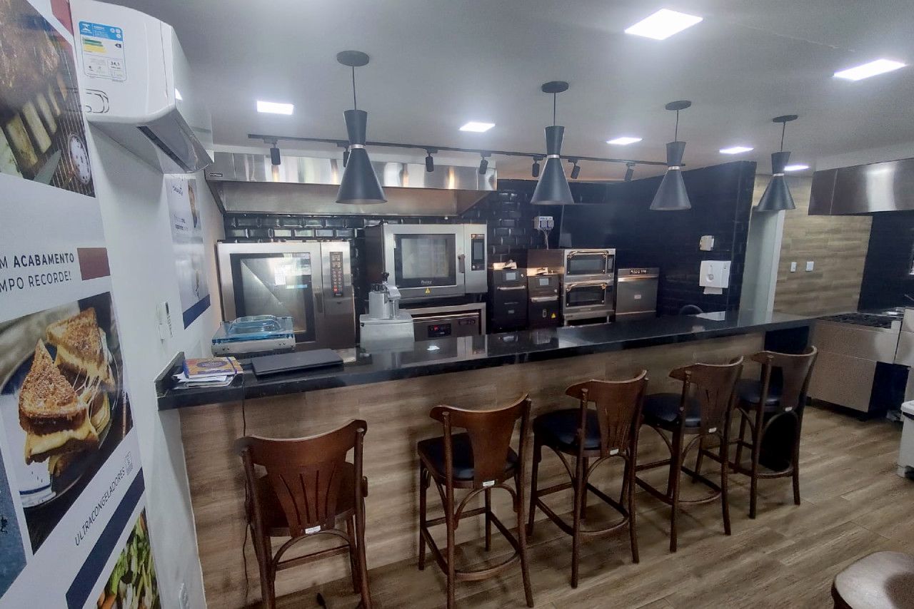Uma cozinha com um balcão longo, cadeiras e uma geladeira.