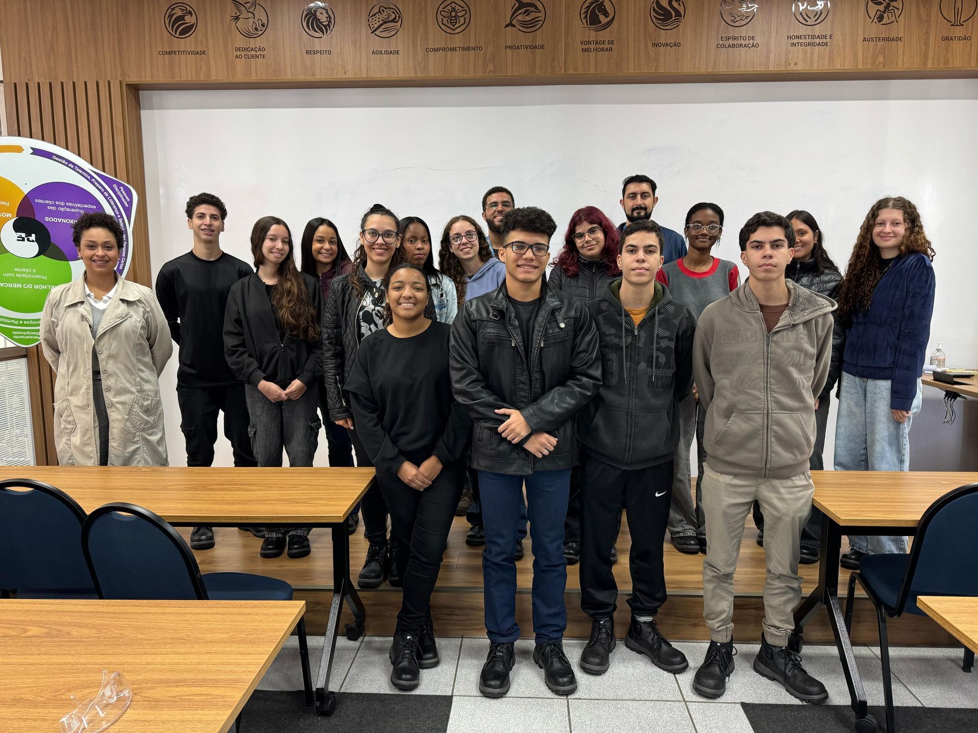 Um grupo de jovens está posando para uma foto em uma sala de aula.
