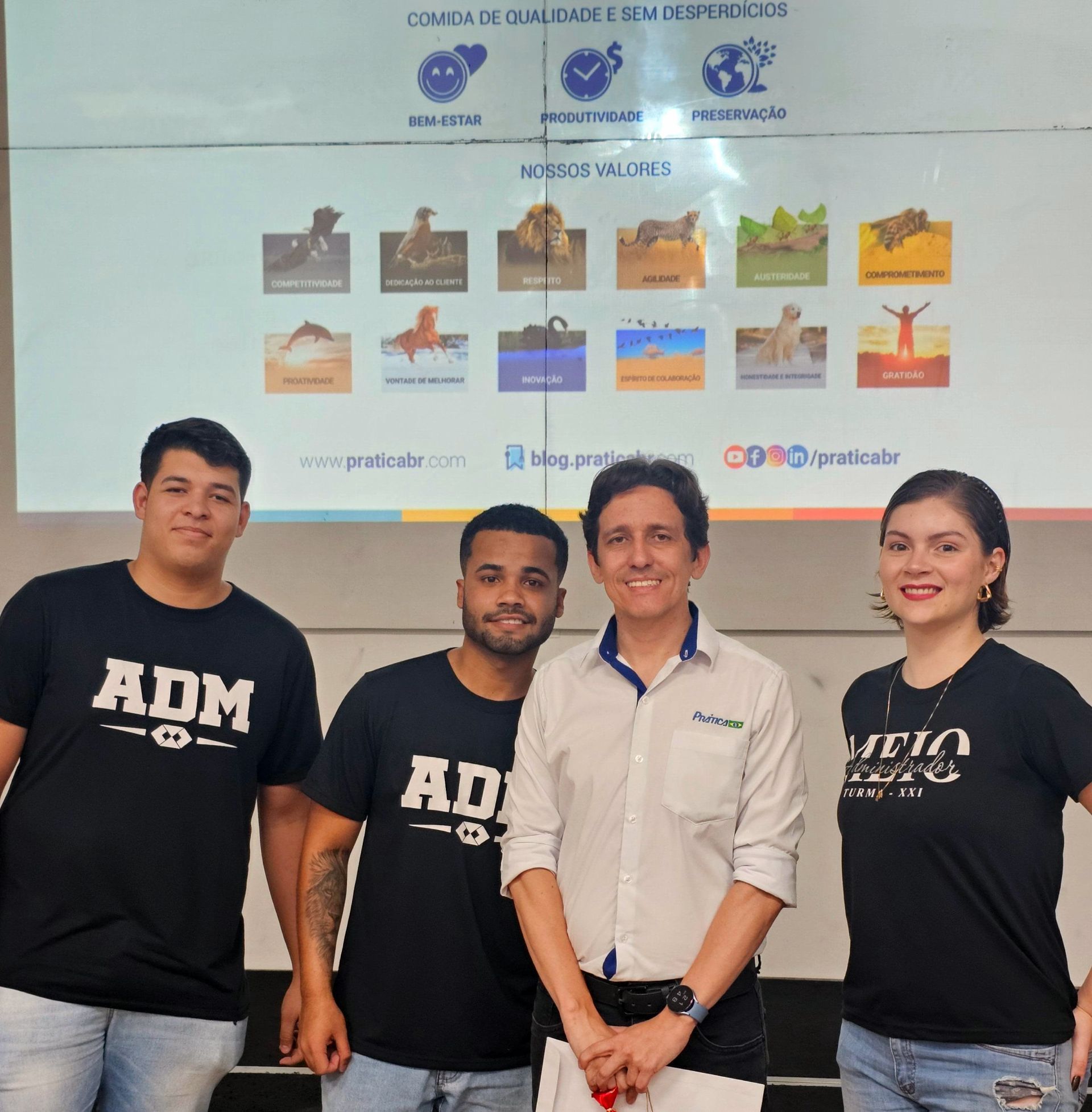 Um grupo de pessoas está posando para uma foto com uma delas vestindo uma camisa de adm