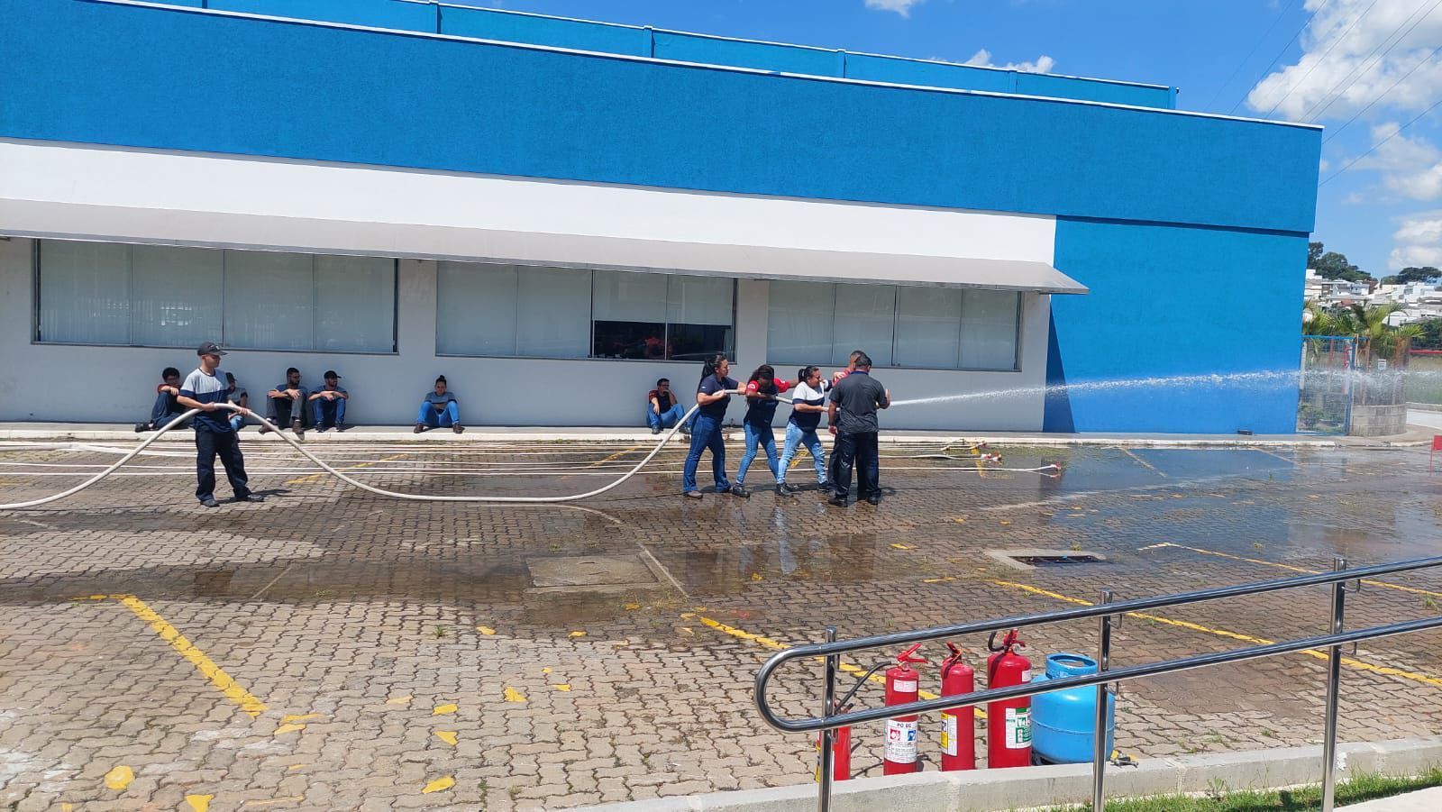 Um grupo de pessoas está jogando água no chão em frente a um prédio azul.