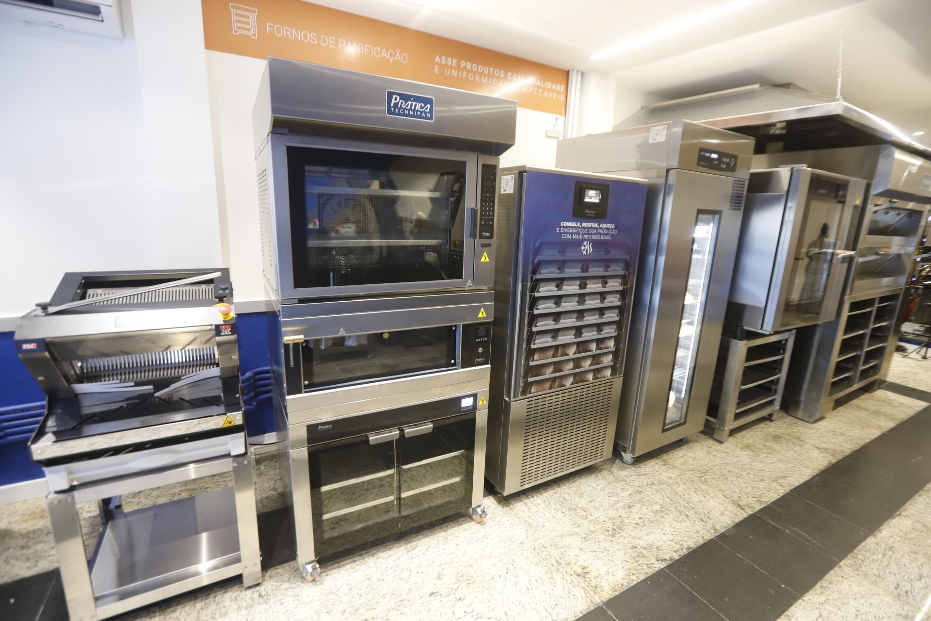 Eletrodomésticos de cozinha comercial alinhados, incluindo fornos e fermentadores.