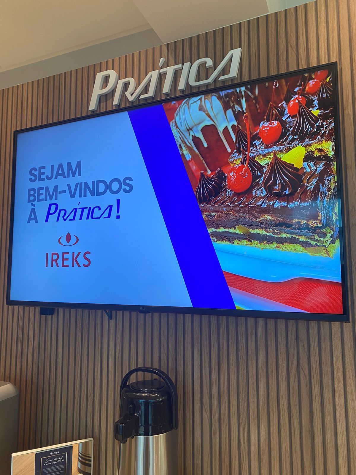 Uma grande TV de tela plana está pendurada em uma parede de madeira.