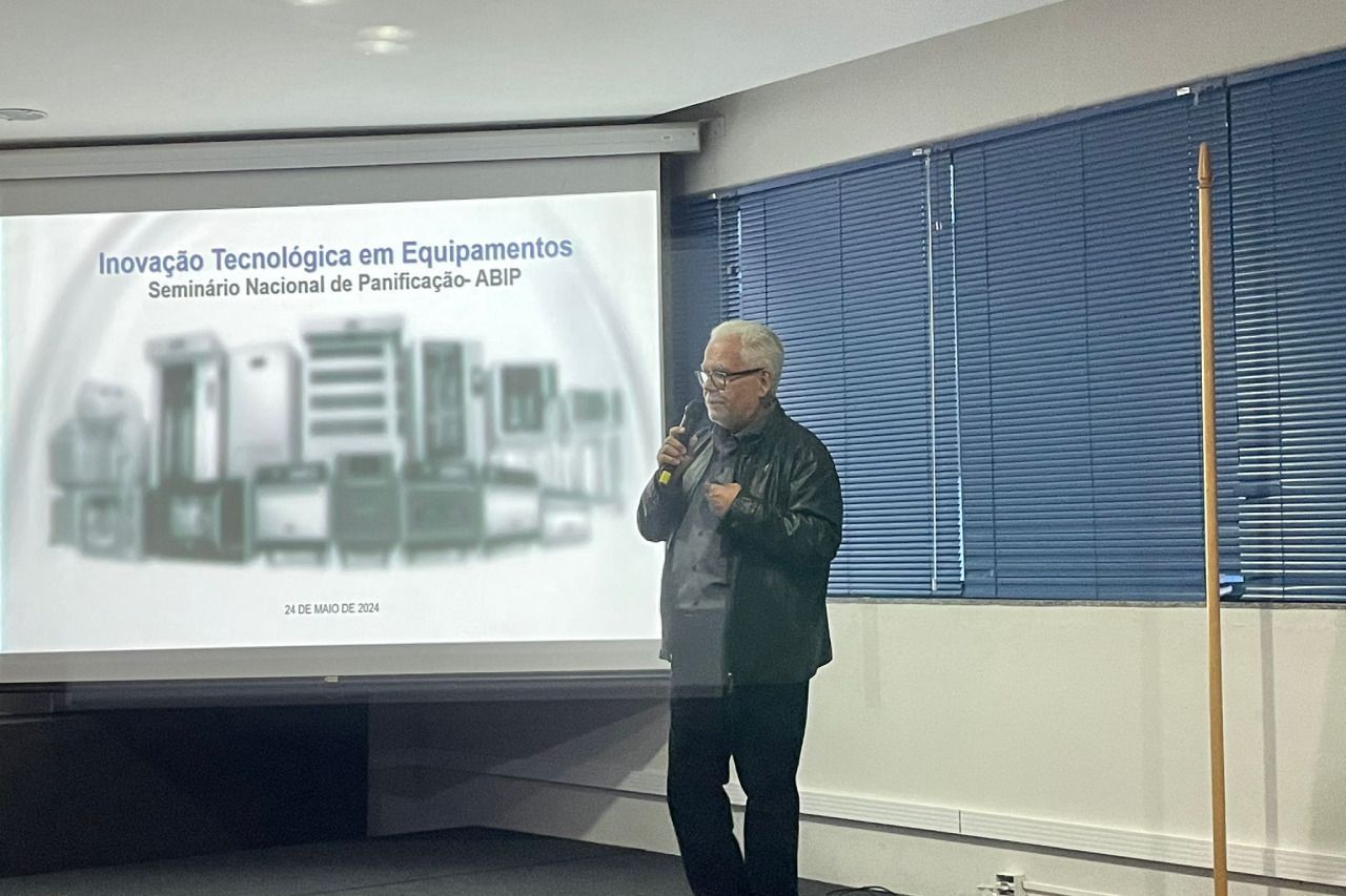 Um homem está fazendo uma apresentação em frente a uma tela de projetor.