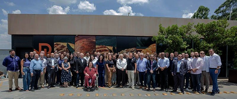 Grande grupo de pessoas em pé do lado de fora de um prédio com a letra
