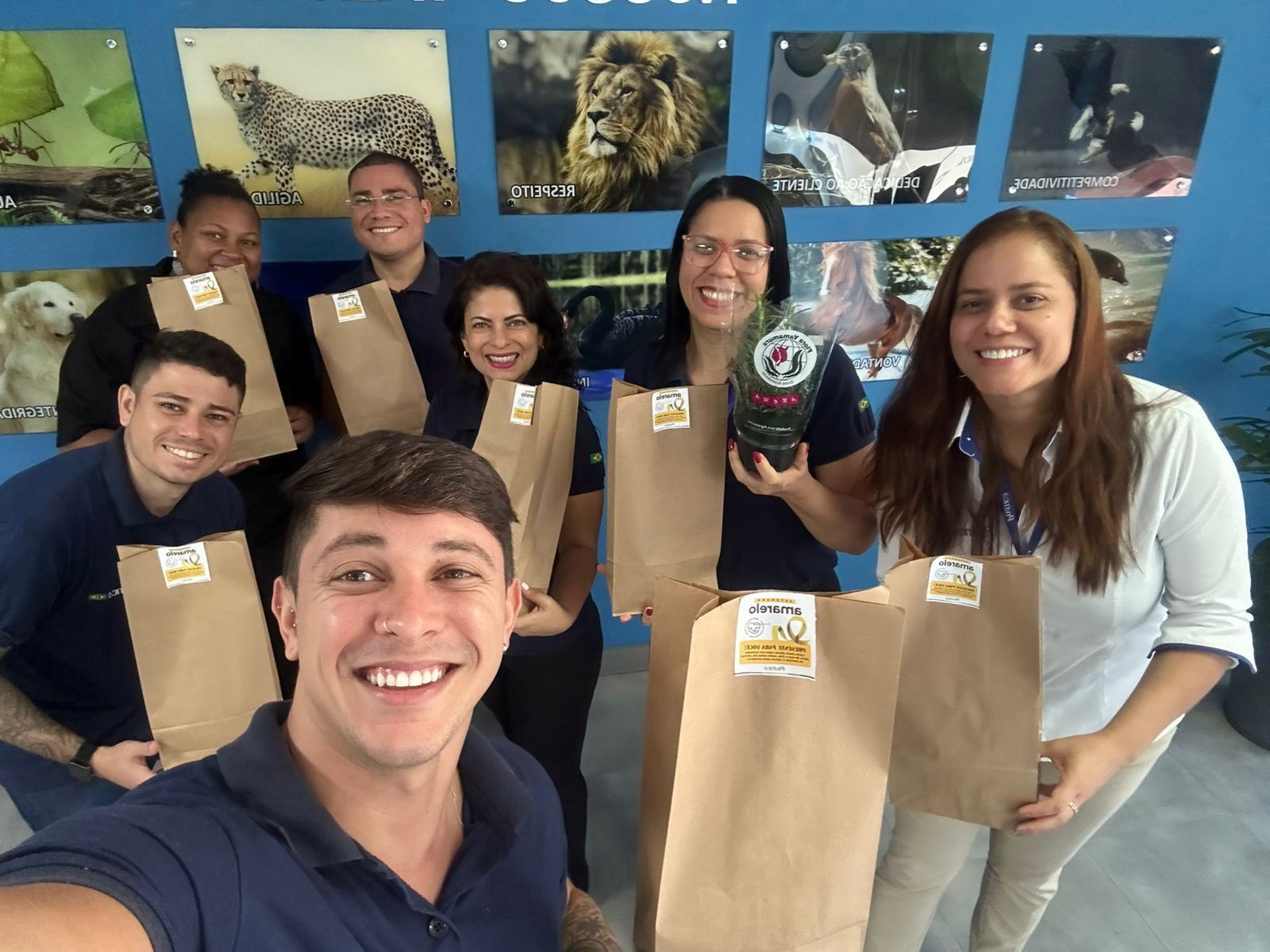 Um grupo de pessoas está posando para uma foto segurando sacolas marrons.