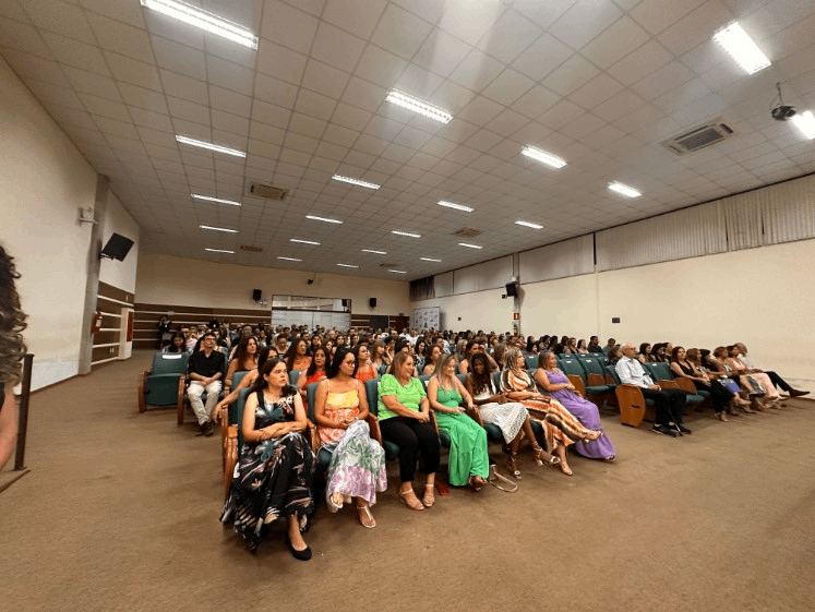 Um grande grupo de pessoas está sentado em um grande auditório.