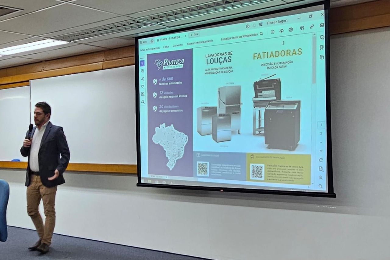 Um homem está fazendo uma apresentação em frente a uma tela grande.