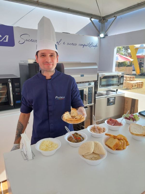 Um homem com chapéu de chef está segurando um prato de comida