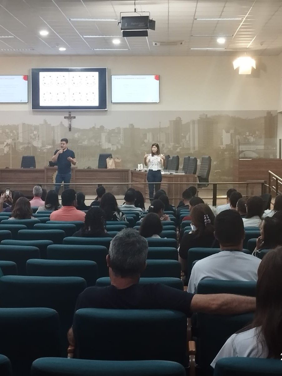 Um grupo de pessoas está sentado em um auditório assistindo a uma apresentação
