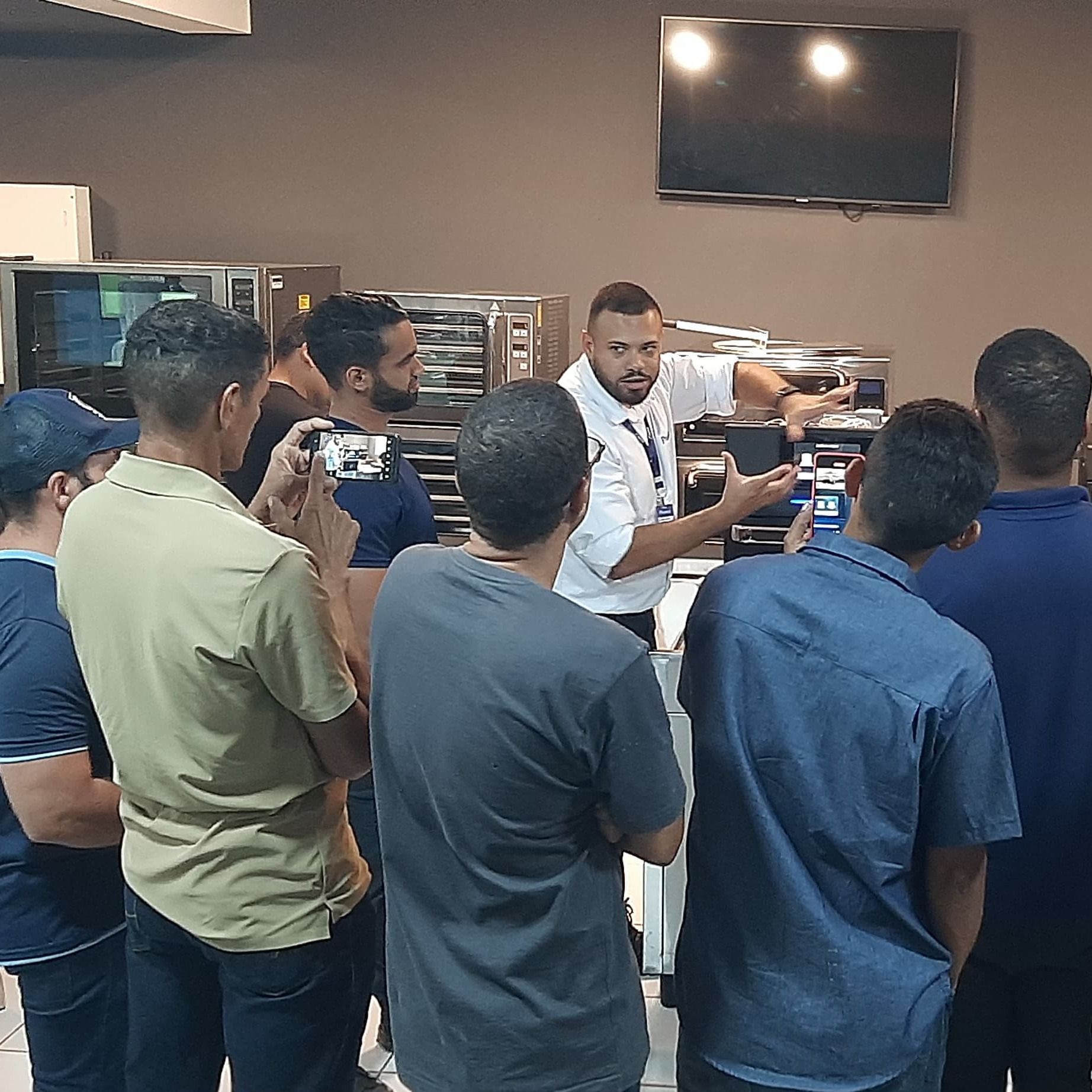 Um grupo de homens está em volta de um homem que está fazendo uma apresentação.