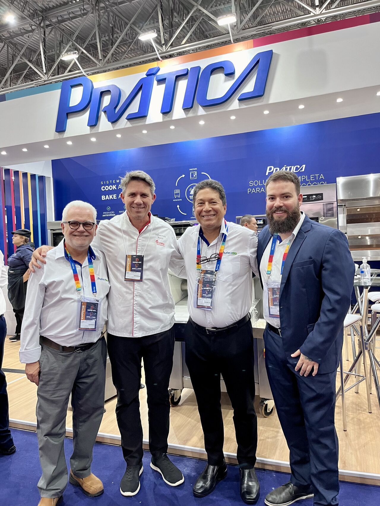 Quatro homens estão posando para uma foto em frente a uma placa de prática