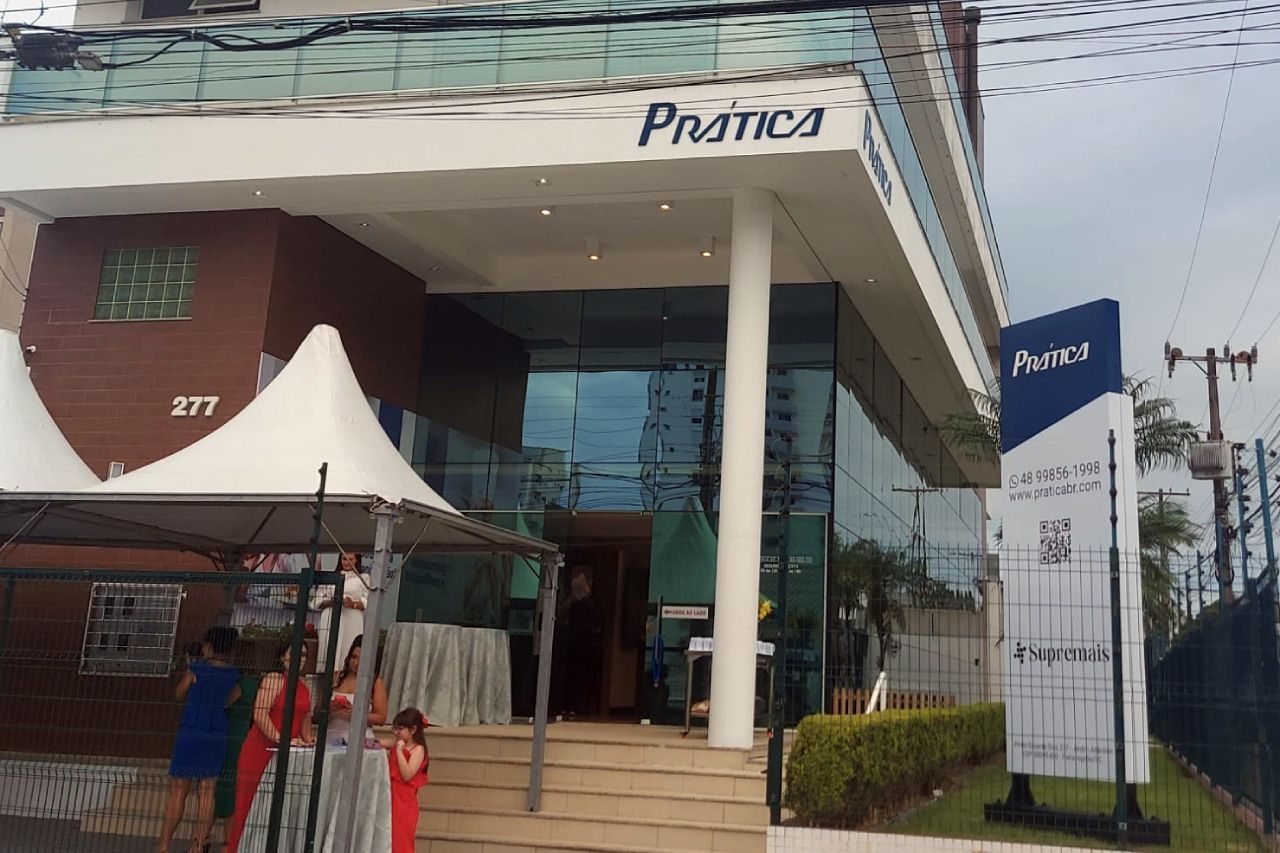 Um grupo de pessoas está do lado de fora de um prédio com uma tenda na frente.