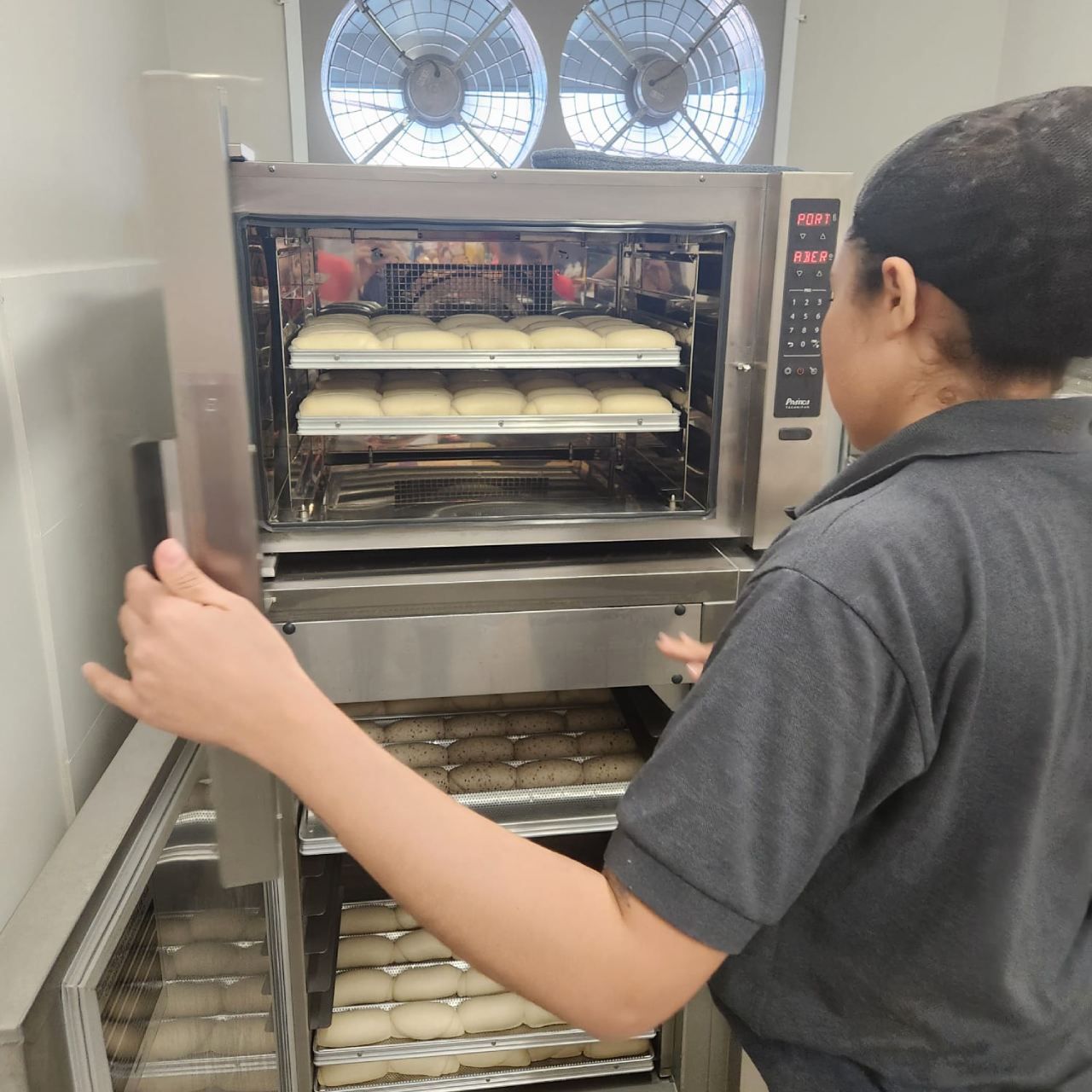 Um homem está parado em frente a um forno de aço inoxidável
