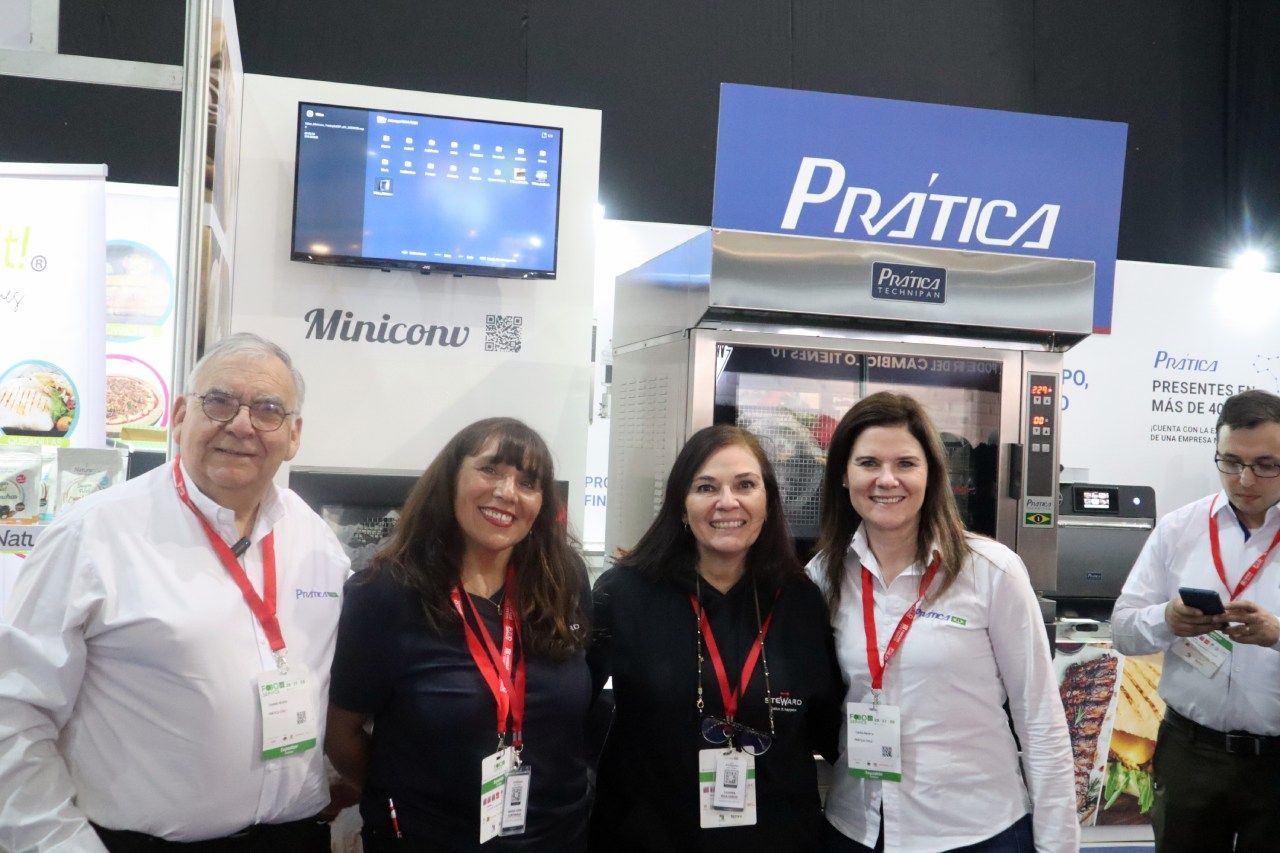 Um grupo de pessoas está posando para uma foto em frente a uma placa de prática.
