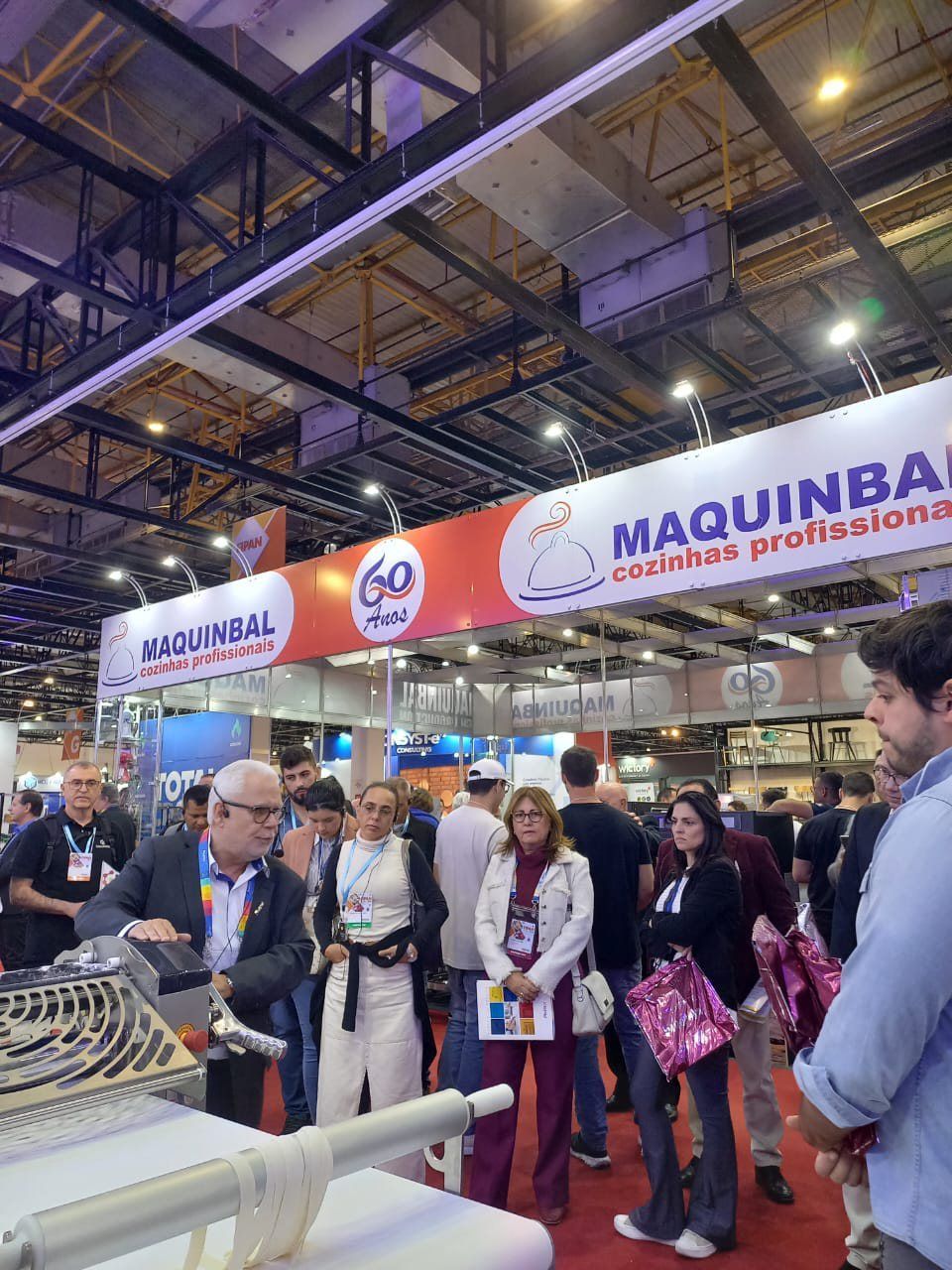 Um grupo de pessoas sob uma placa que diz maquinba