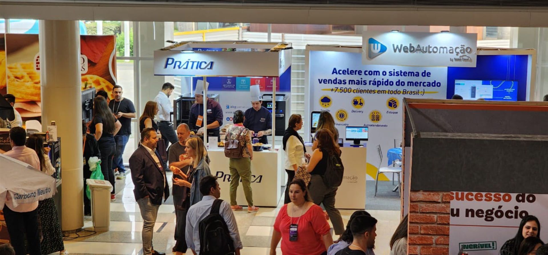Um grupo de pessoas está em frente a um estande em uma convenção.