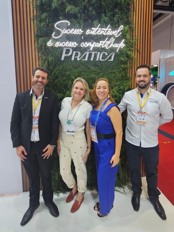 Um grupo de pessoas em pé em frente a uma placa que diz pratica